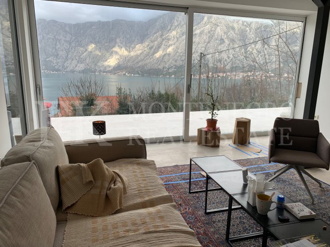This newly built house with 143 sqm and an additional guesthouse (51 sqm) offers a prime location, just 330 meters from the coast, with an impressive panoramic view of the Bay of Kotor and the surrounding mountains.